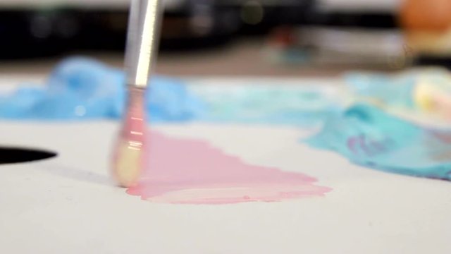Artist mixes different colors of acrylic paint with a brush for drawing. Preparation of colors for drawing pictures