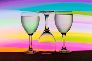 Three wine glasses in a row with colorful light painting behind