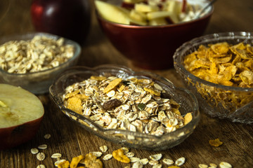 Muesli with dried fruit, Barley flake, fresh organic red apple,  and corn flakes. Close up photo of a cereal grain product and apples