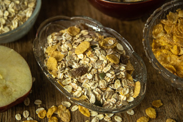 Muesli with dried fruit, Barley flake, fresh organic red apple,  and corn flakes. Close up photo of a cereal grain product and apples