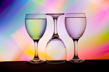 Three wine glasses in a row with colorful light painting behind