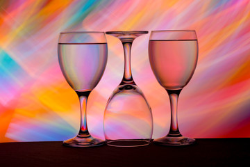 Three wine glasses in a row with colorful light painting behind