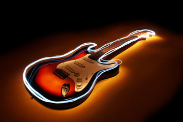 Electric guitar with edge glow on dark blue background. Lightpainting technique.