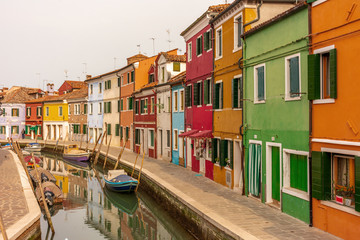 Italy, Venice, Burano, canals and boats among the typical colored houses.