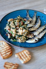 Grilled sardines and salad made with chicory, white beans and dried tomatoes. Selective focus. 