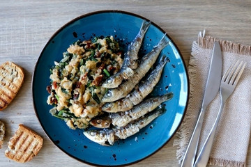 Grilled sardines and salad made with chicory, white beans and dried tomatoes. Selective focus. 