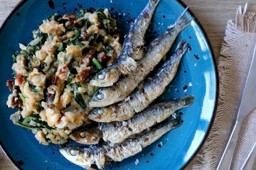 Grilled sardines and salad made with chicory, white beans and dried tomatoes. Selective focus. 
