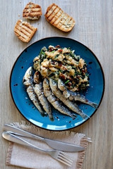Grilled sardines and salad made with chicory, white beans and dried tomatoes. Selective focus. 
