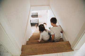 Children play at home on the stairs. Gray homewear. Son and daughter Brother and sister. Sit on the...