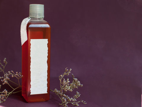 Bottle of shampoo or shawer gel with herbs on purple background with copy space. Beauty, skin and hair care concept. Natural cosmetic product.