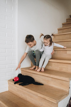 Children play at home on the stairs. Gray homewear. Son and daughter Brother and sister. Play with the cat. Black cat.