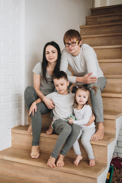 Family in gray home clothes. In the house on wooden steps. Big h
