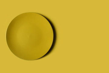 Yellow dish on a yellow backgroung. Deep shadow. Postcard, Design. Pace for text, copy space.