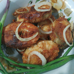 	Many pieces of fried fish with onion rings in a plate 