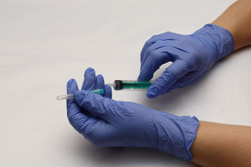 Blue gloves on hand. Syringe with a needle. Preparation for the injection of the drug.