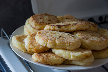 Hot tasty baked cheese pancakes in the plate standing on the gas stove. Breakfast