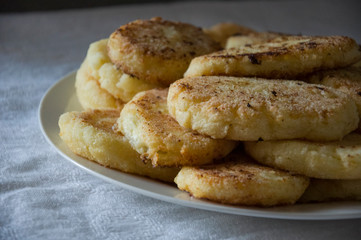 Hot tasty baked cheese pancakes in the plate standing on the gas stove. Breakfast