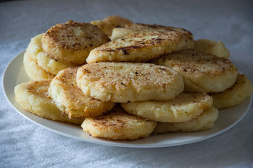 Hot tasty baked cheese pancakes in the plate standing on the gas stove. Breakfast