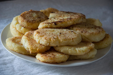 Hot tasty baked cheese pancakes in the plate standing on the gas stove. Breakfast