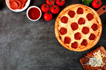 Traditional pepperoni pizza, top view, corner border against a dark background with copy space