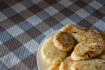 Hot tasty baked cheese pancakes in the plate standing on the  checkered tablecloth. Breakfast