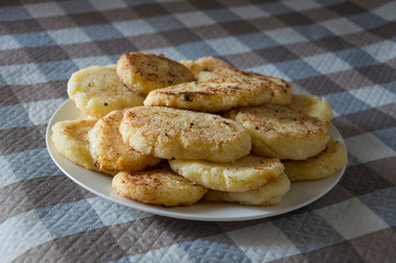 Hot tasty baked cheese pancakes in the plate standing on the  checkered tablecloth. Breakfast
