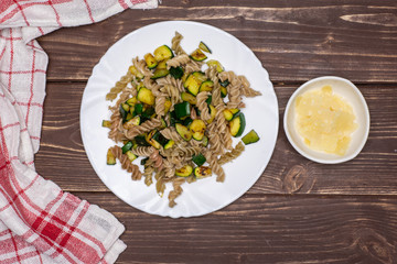 Add parmesan cheese. recipe step by step fusilli pasta with zucchini on white porcelain plate with a tea towel flatlay on brown wood