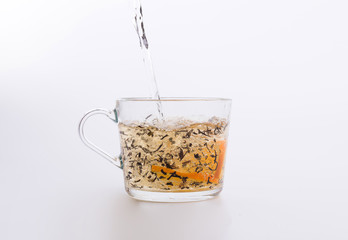 black tea with orange pouring into glass cup isolated on white