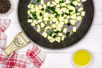 Recipe step by step fusilli pasta with zucchini chopped square pieces on a frying pan with a tea...