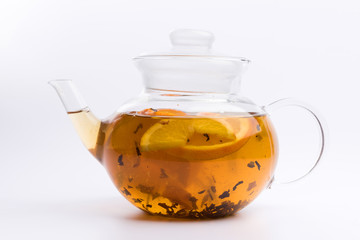 Glass teapot with herbal tea nad fresh orange isolated on white background