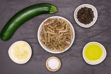Set of ingredients. recipe step by step fusilli pasta with zucchini flatlay on grey stone