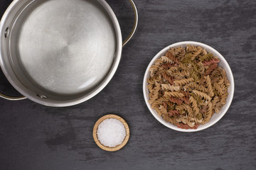 Add pasta to a pot to boil. recipe step by step fusilli pasta with zucchini with a stock pot flatlay on grey stone