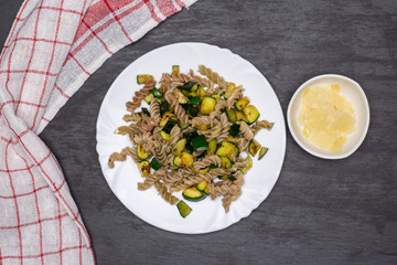 Add parmesan cheese. recipe step by step fusilli pasta with zucchini on white porcelain plate with a tea towel flatlay on grey stone