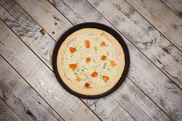 Round pizza dough is in the pan. The process of cooking pizza, stacking ingredients on the dough.