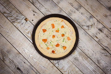Round pizza dough is in the pan. The process of cooking pizza, stacking ingredients on the dough.