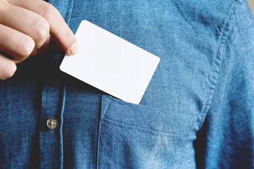 Young man is taking a blank card in the pocket of his shirt.
