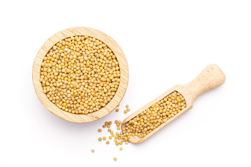 Lot of whole white mustard seeds with wooden bowl and wooden scoop flatlay isolated on white...