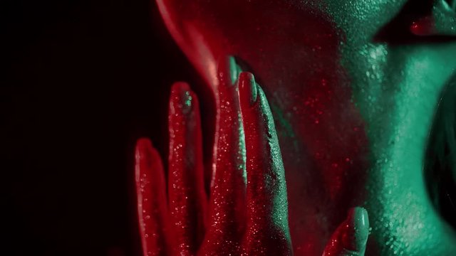 Fashion portrait of woman touching her neck with fingertips in glitter and in neon lights in 80's style, video portrait with green and red mixed neon on dark background, Shot on blackmagic 422 prores