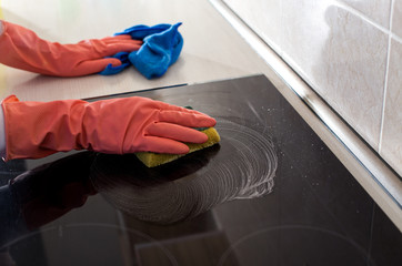 Woman cleaning induction stove in kitchen