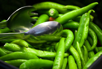 green peppers and fork in plate on black background