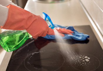 Woman cleaning induction stove in kitchen