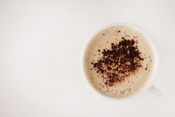white cup with cappuccino and frothy and grated chocolate on a beige background and free space for the inscription on the left