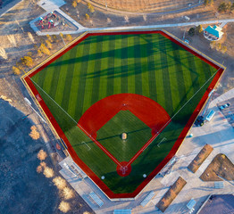 Aerial drone wide angle view of a green baseball field diamond in the morning sunlight ready for...