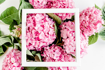 Carved, white frame decorated of pink hydrangea flowers on white background. Floral concept. Flat lay, top view. 