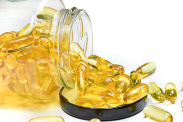 Close up of fish oil capsules in a glass bottle on white background. Omega 3. Vitamin E. Supplementary food background.