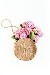 Fototapeta na wymiar Pink bouquet of hydrangea in a straw bag on white background. Minimal floral concept. Flat lay, top view. 