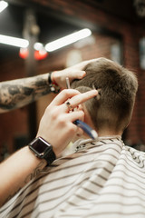 man being trimmed with electric clipper machine in barbershop.Male beauty treatment concept. Young guy getting new haircut in barber salon