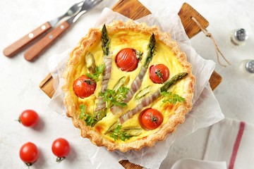 Tart pie with cheese, asparagus, bacon and cherry tomatoes. Top view.