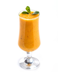 Orange smoothie in a tall glass decorated with a leaf of mint on an isolated white background
