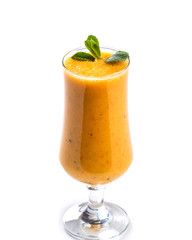 Orange smoothie in a tall glass decorated with a leaf of mint on an isolated white background